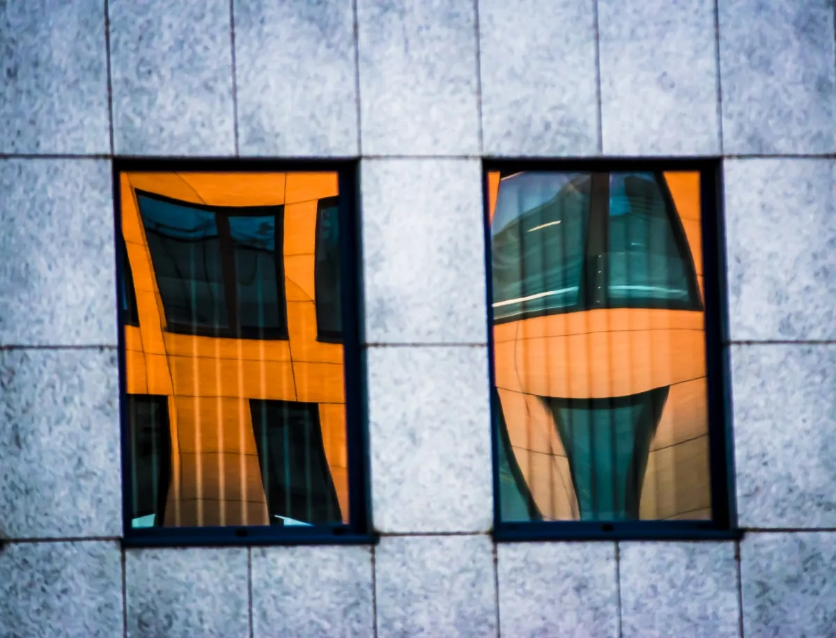 Two orange-framed windows reflected in polished stone panels